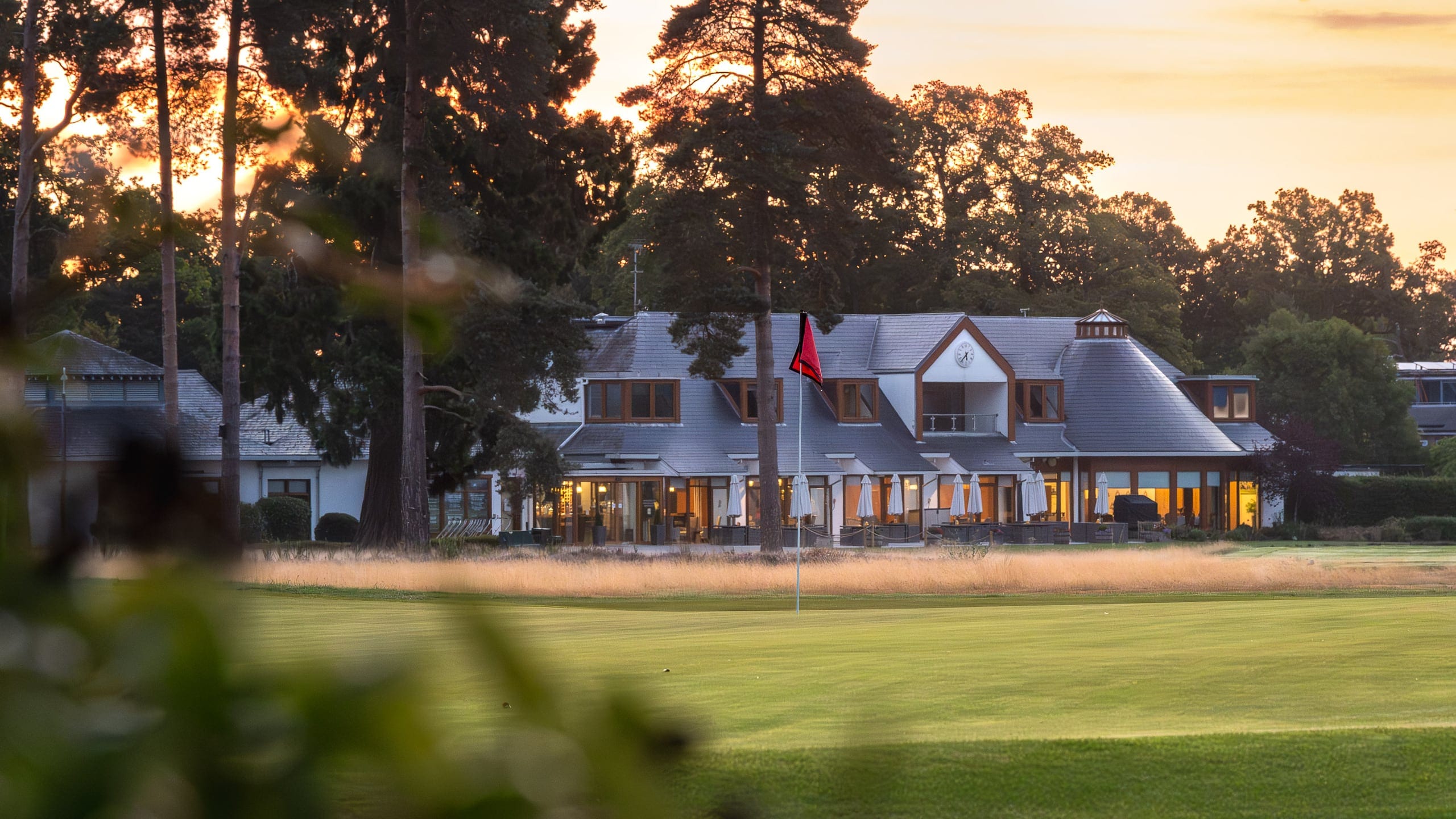 The clubhouse lit at dusk behind the eighteenth