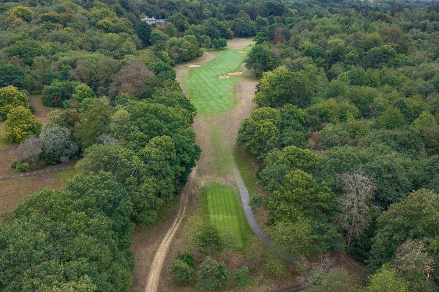 Aerial view of a parkland fairway curving between the trees