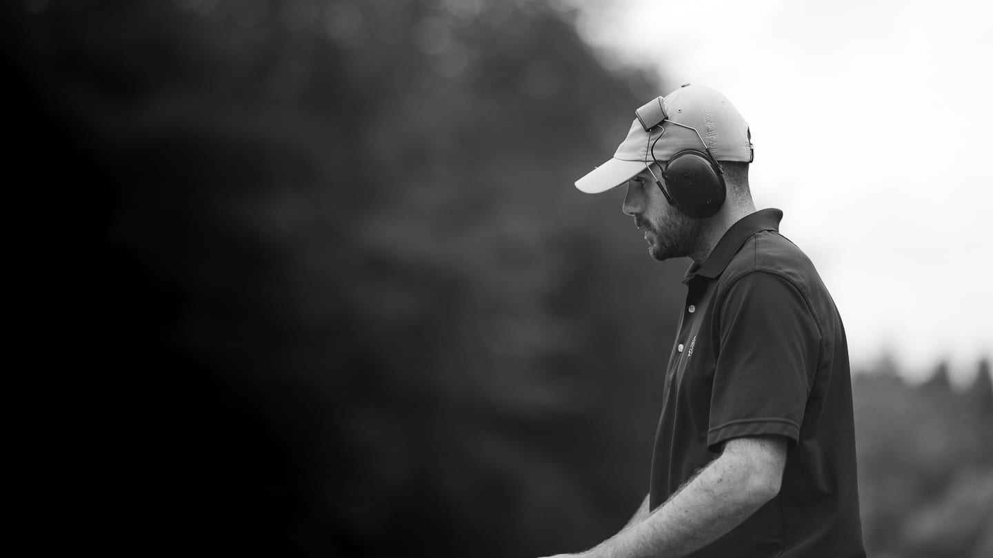 A greenkeeper in ear defenders, black and white