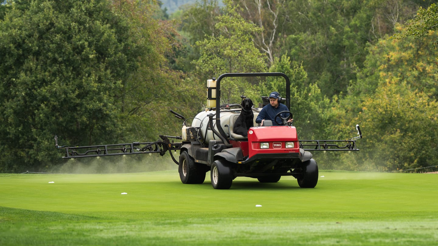 A sprayer working across a green, booms extended
