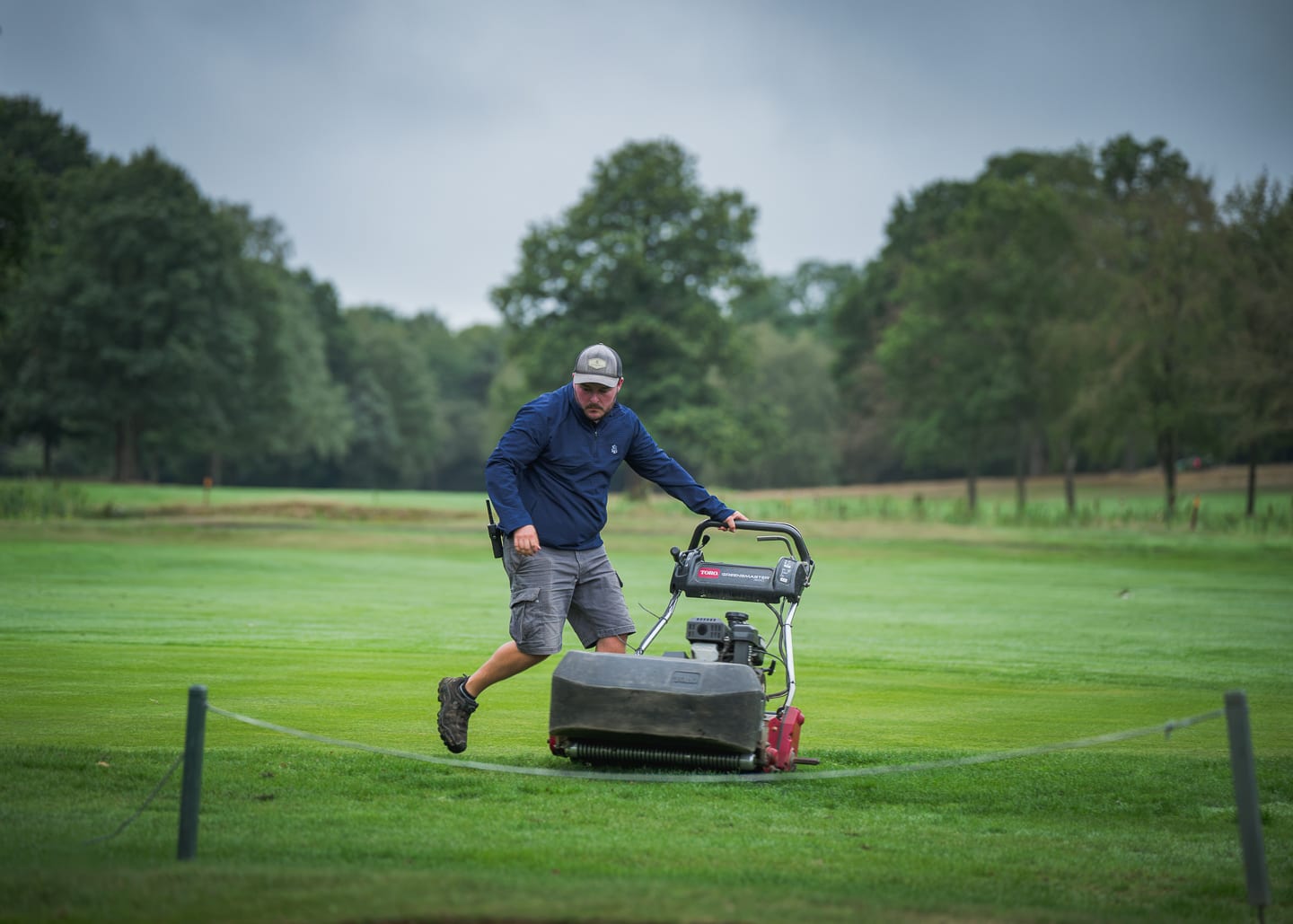 Low angle on the cutting units and brush of a pedestrian mower